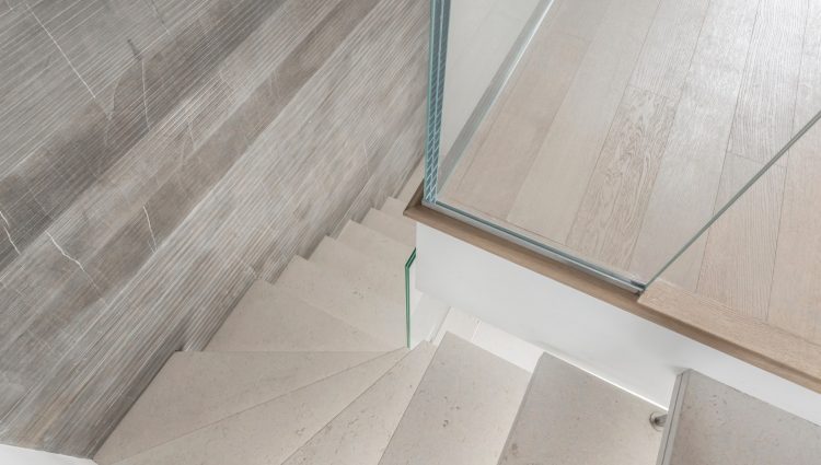 Grey microcement stairs with glass handrail. Stairs viewed from above. Modern design and innovative material. Glass railing.